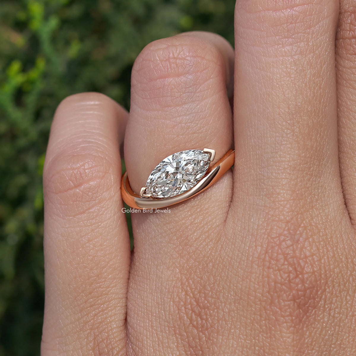 Rose-gold marquise-cut lab diamond solitaire ring on finger, angled front