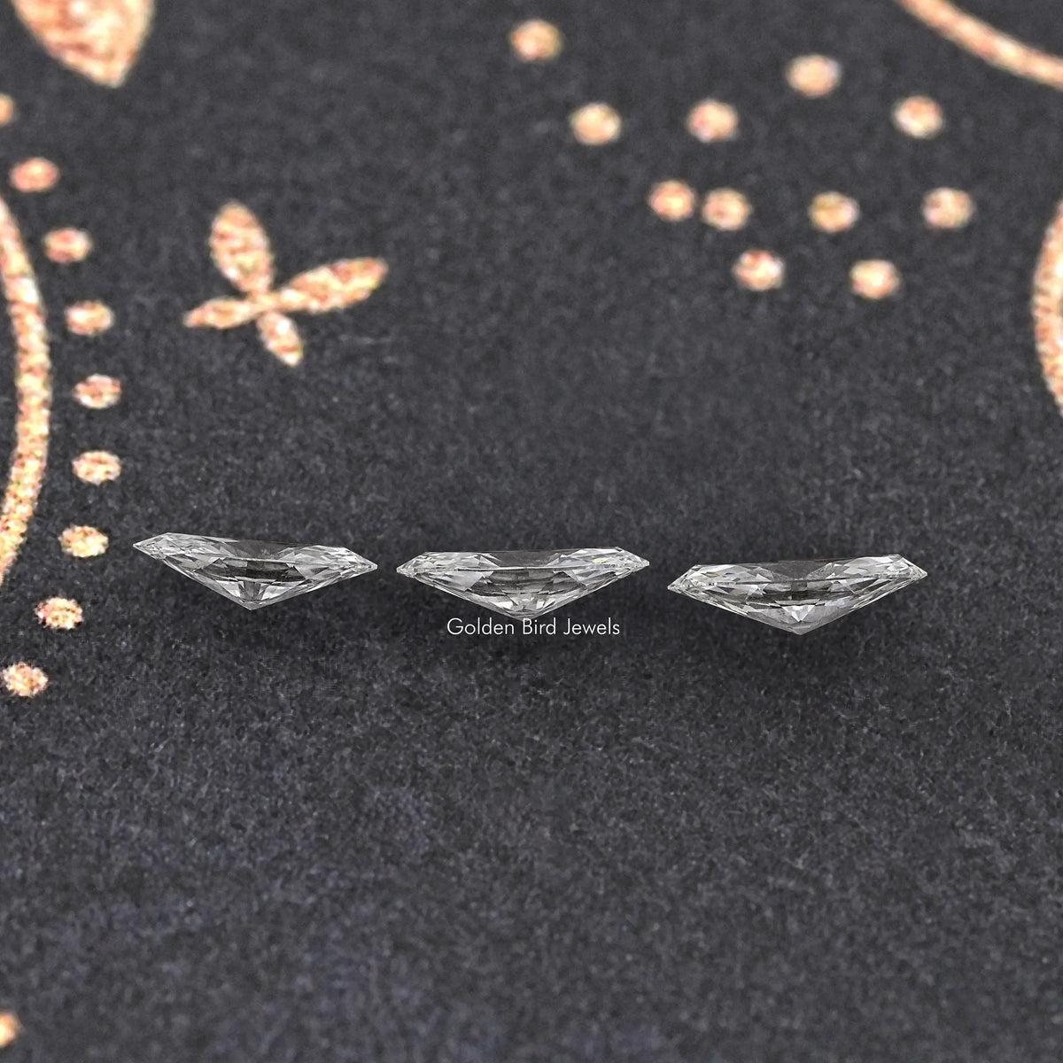 Three marquise-cut loose lab-grown diamonds arranged on dark fabric