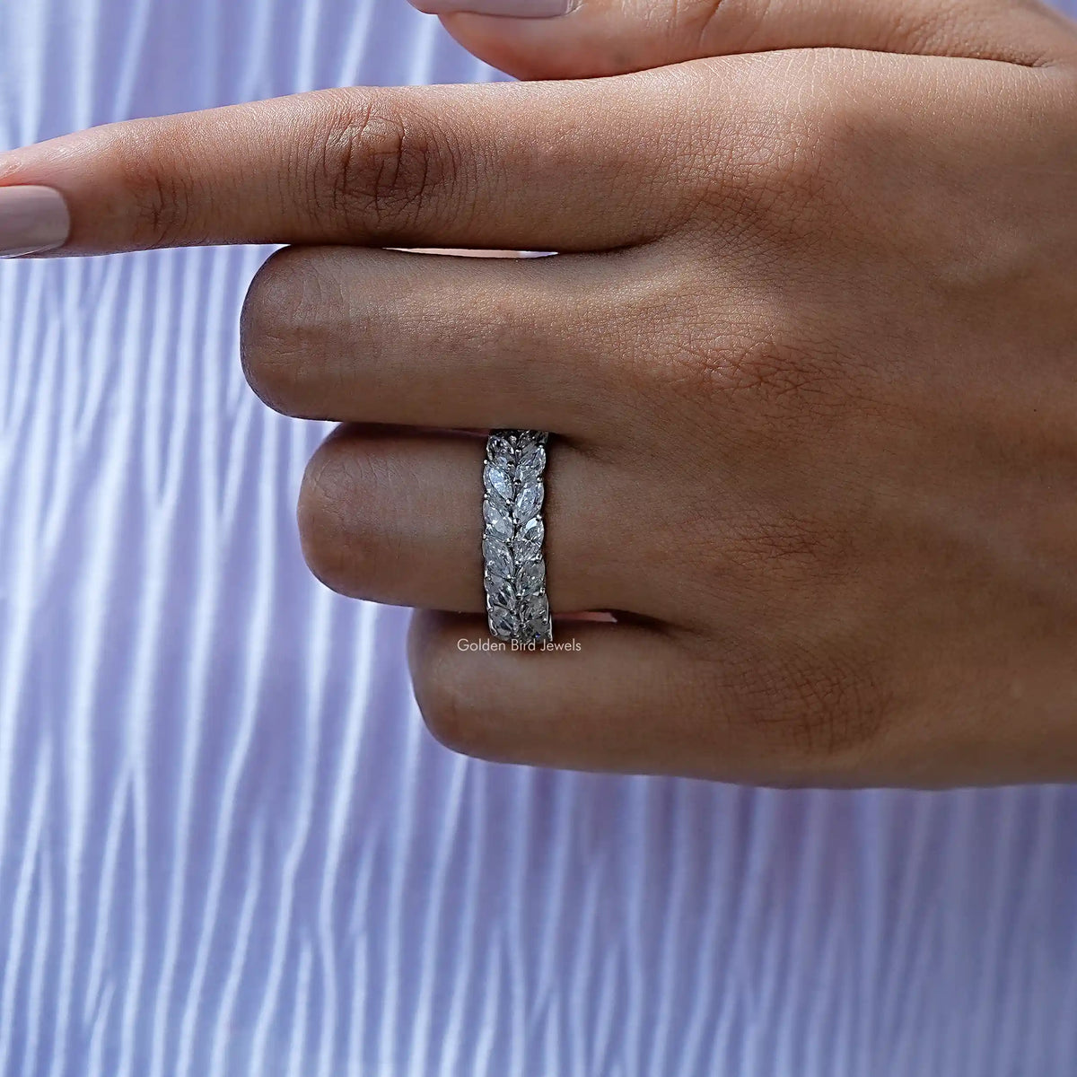 Silver-tone marquise-cut moissanite band on finger, close-up detail