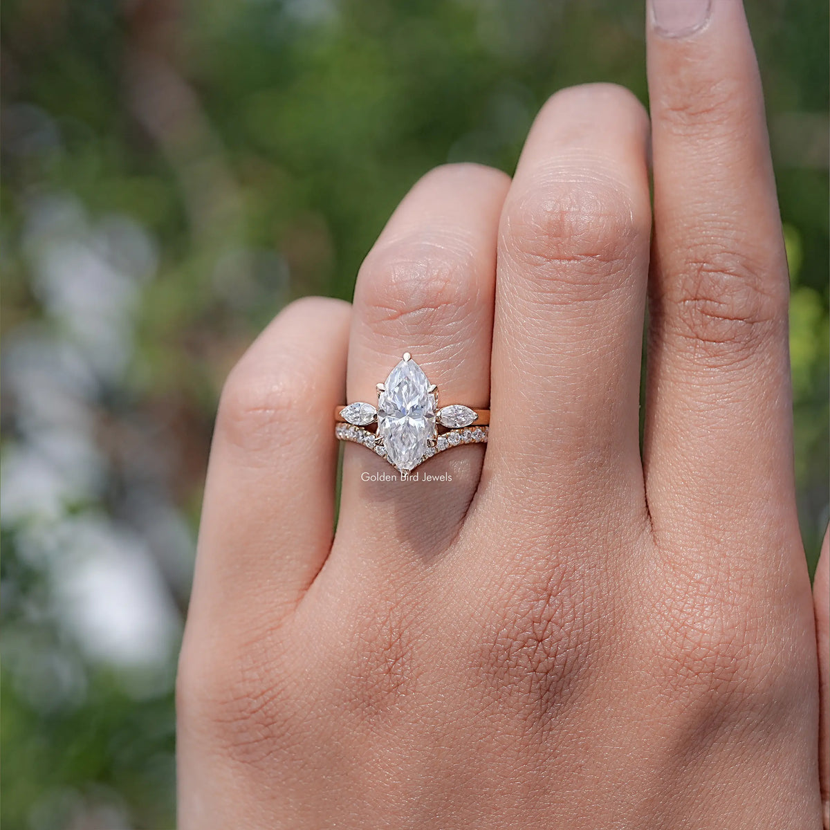 Three-stone bridal ring set with marquise-cut center stone and side stones on an open palm