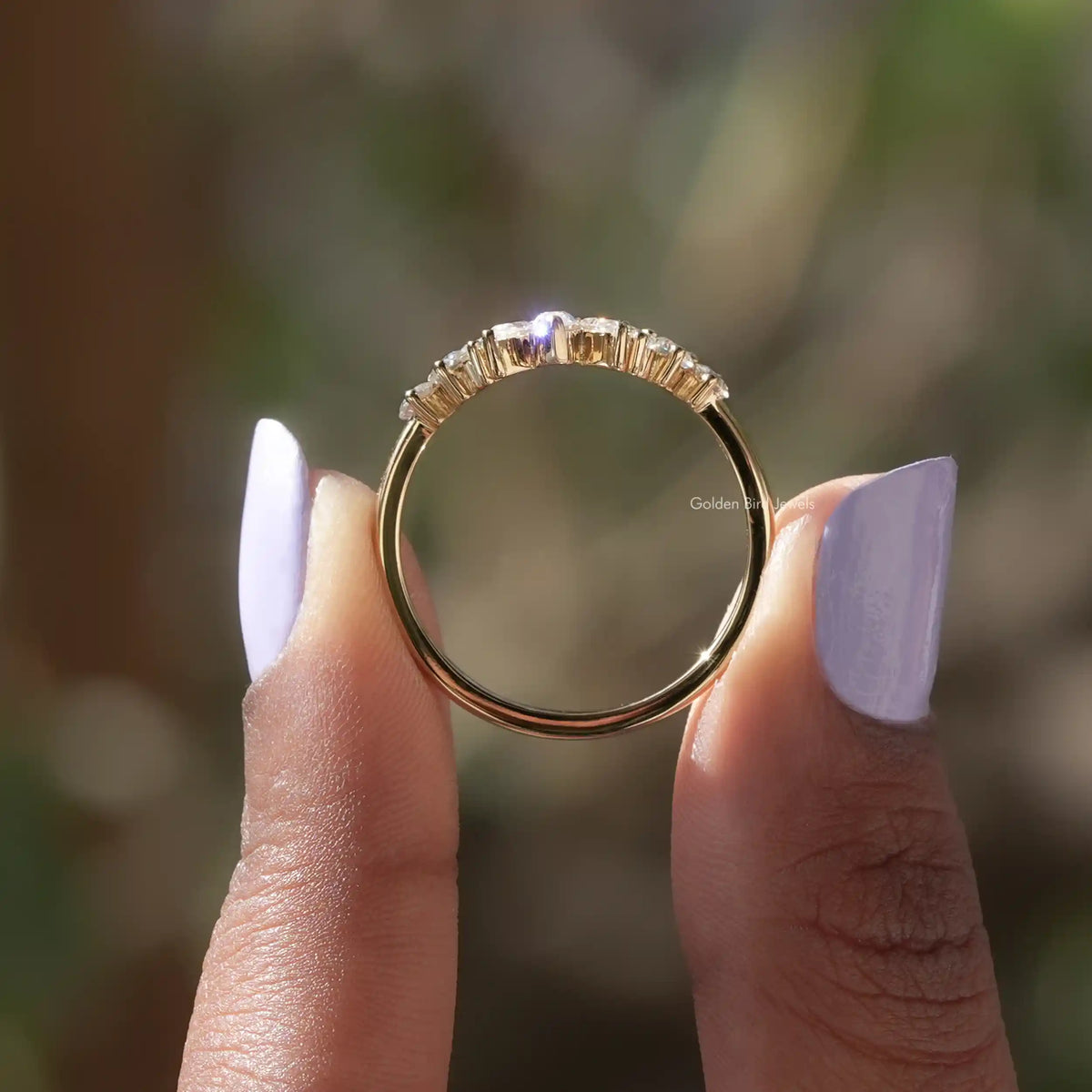 Curved marquise-cut moissanite band viewed from side, gold tone with prongs