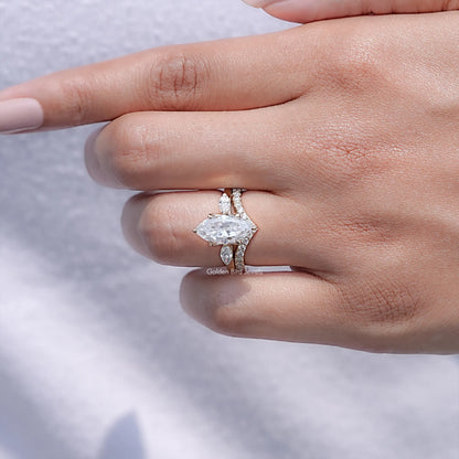 Three-stone bridal ring set on finger, featuring marquise-cut center stone and two side stones