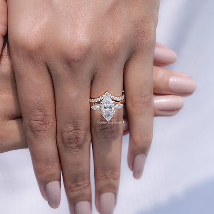 Three-stone bridal ring set with marquise-cut center stone and small side stones, stacked on hand
