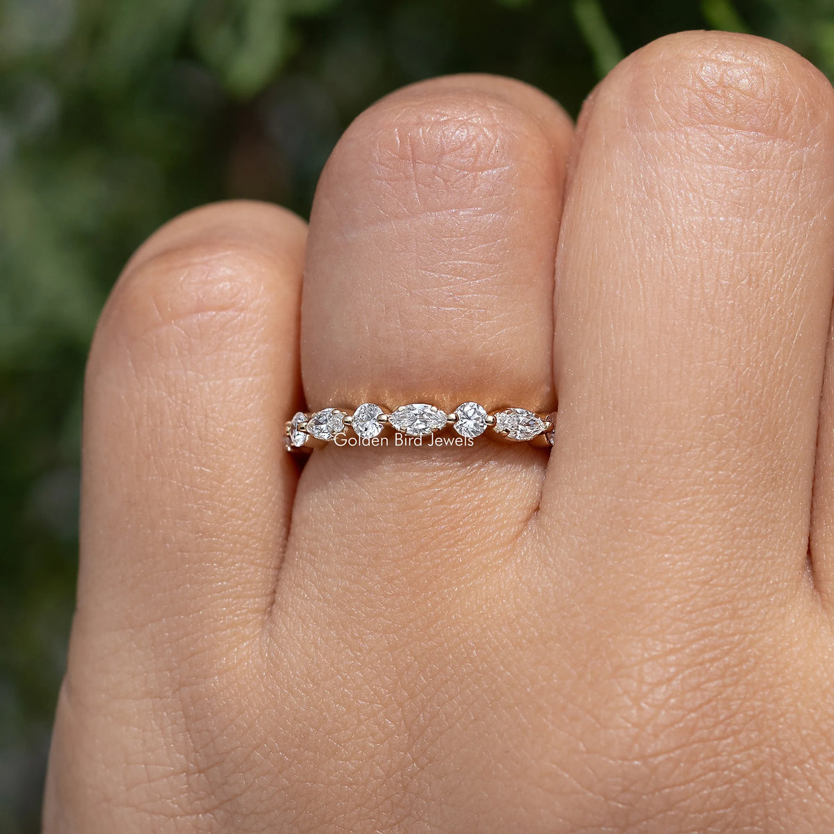 Lab-grown diamond wedding band with marquise and round stones, front view on finger