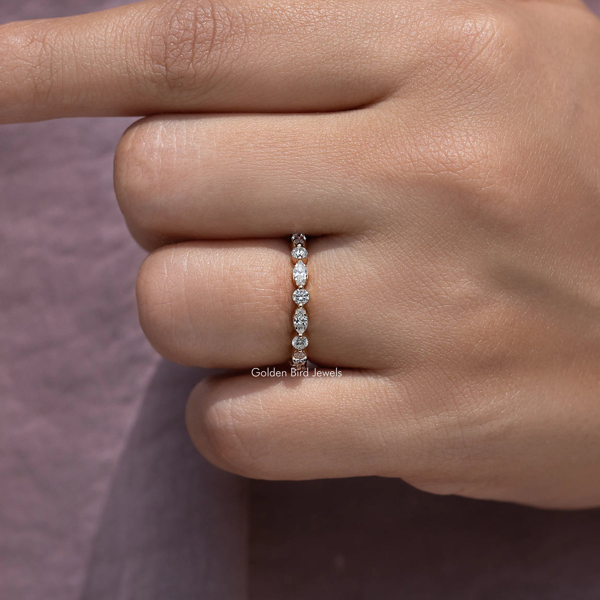 Lab-grown diamond wedding band with marquise and round stones, close-up on finger