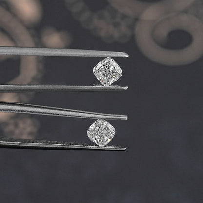 Two cushion-cut lab grown diamond studs held in tweezers, side view