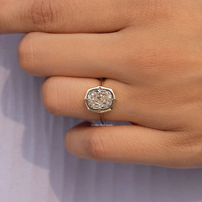 Gold-tone cushion-cut bezel set engagement ring on finger, centered close-up