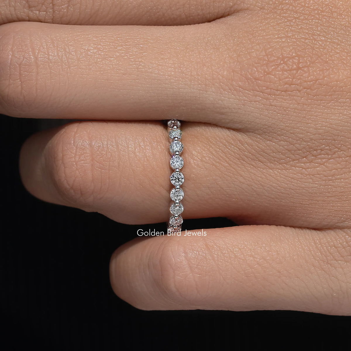 Round moissanite half eternity band detail with linked stone settings on hand