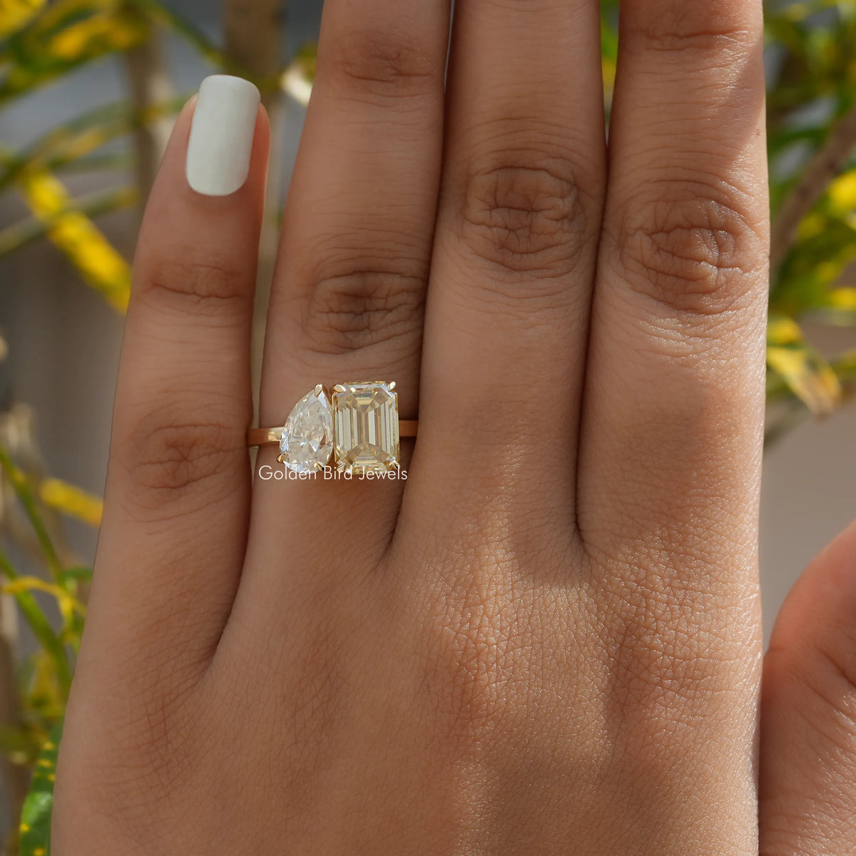 Two-stone toi et moi ring with prong-set stones on finger, gold-toned setting