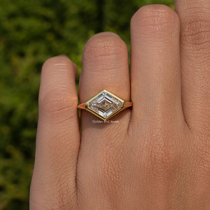 Lozenge-cut moissanite solitaire ring on hand with gold bezel setting on silver band