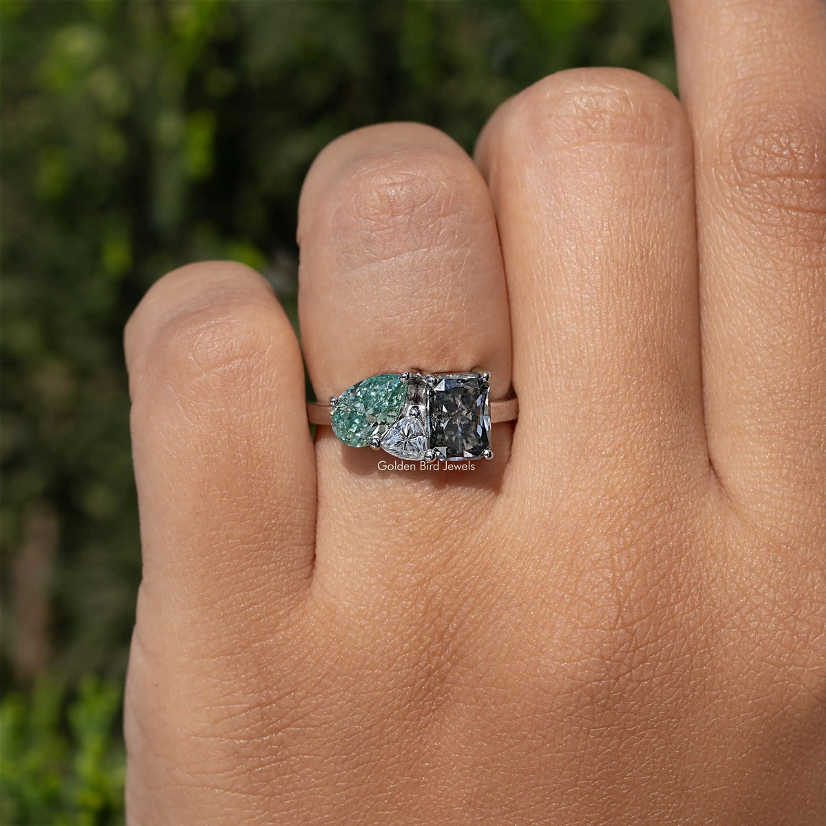 Three-stone moissanite engagement ring with oval green center and two square-cut sides