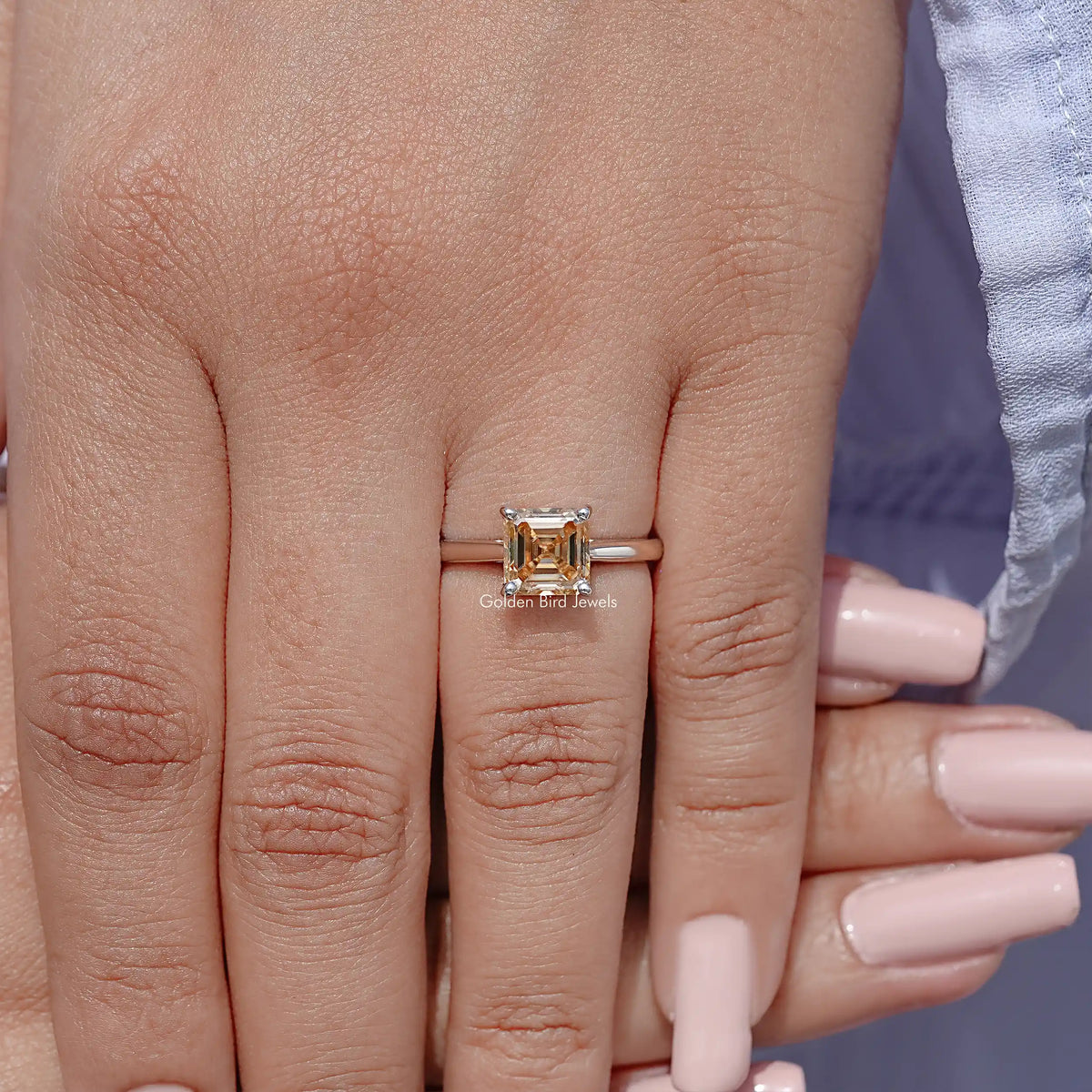 Sterling silver Asscher-cut moissanite solitaire ring on finger, four-prong square center.