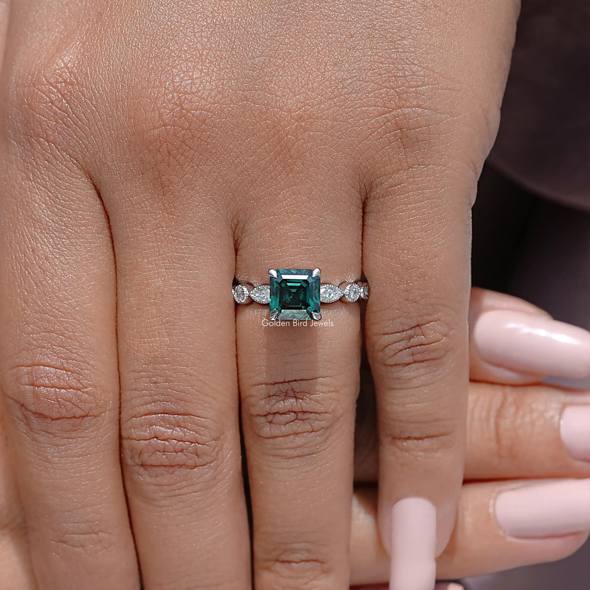Green square-cut center stone ring with small round side stones and silver band