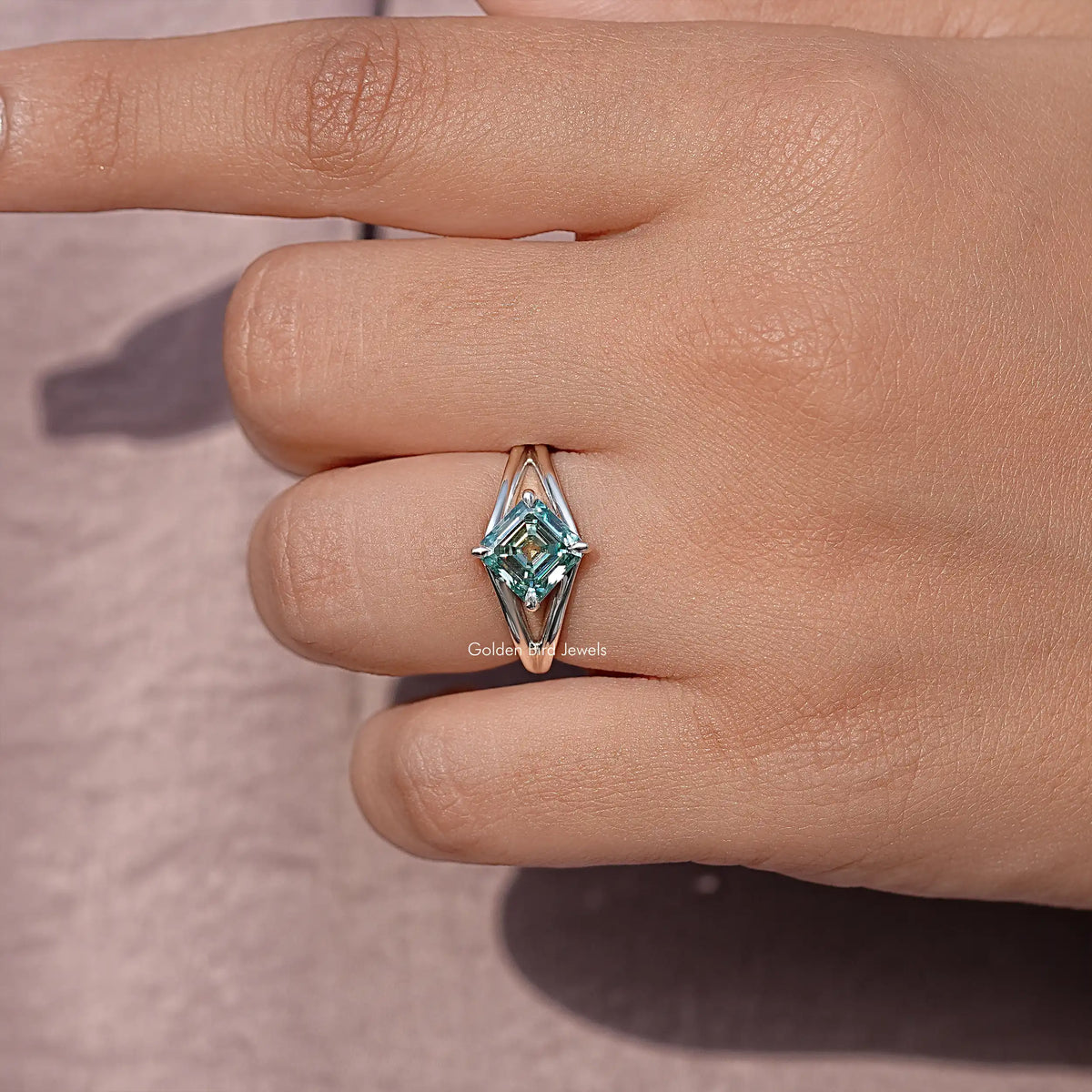 Close-up of sterling silver split shank ring with teal Asscher cut moissanite