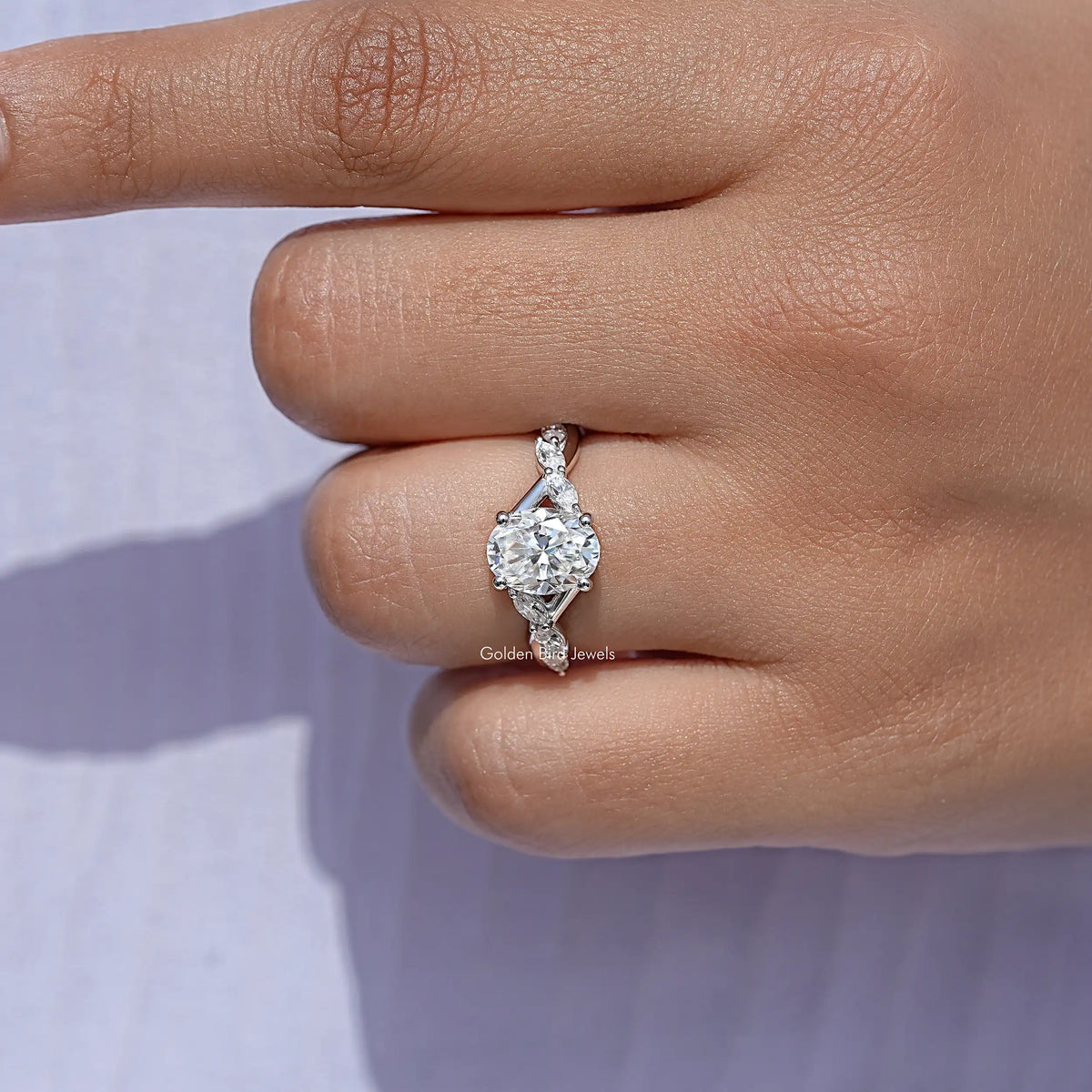 Close-up of oval moissanite solitaire ring with prong setting and floral halo, sterling silver