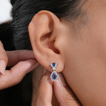Blue pear-cut dangle earrings with diamond halo and drop accent, silver-tone setting