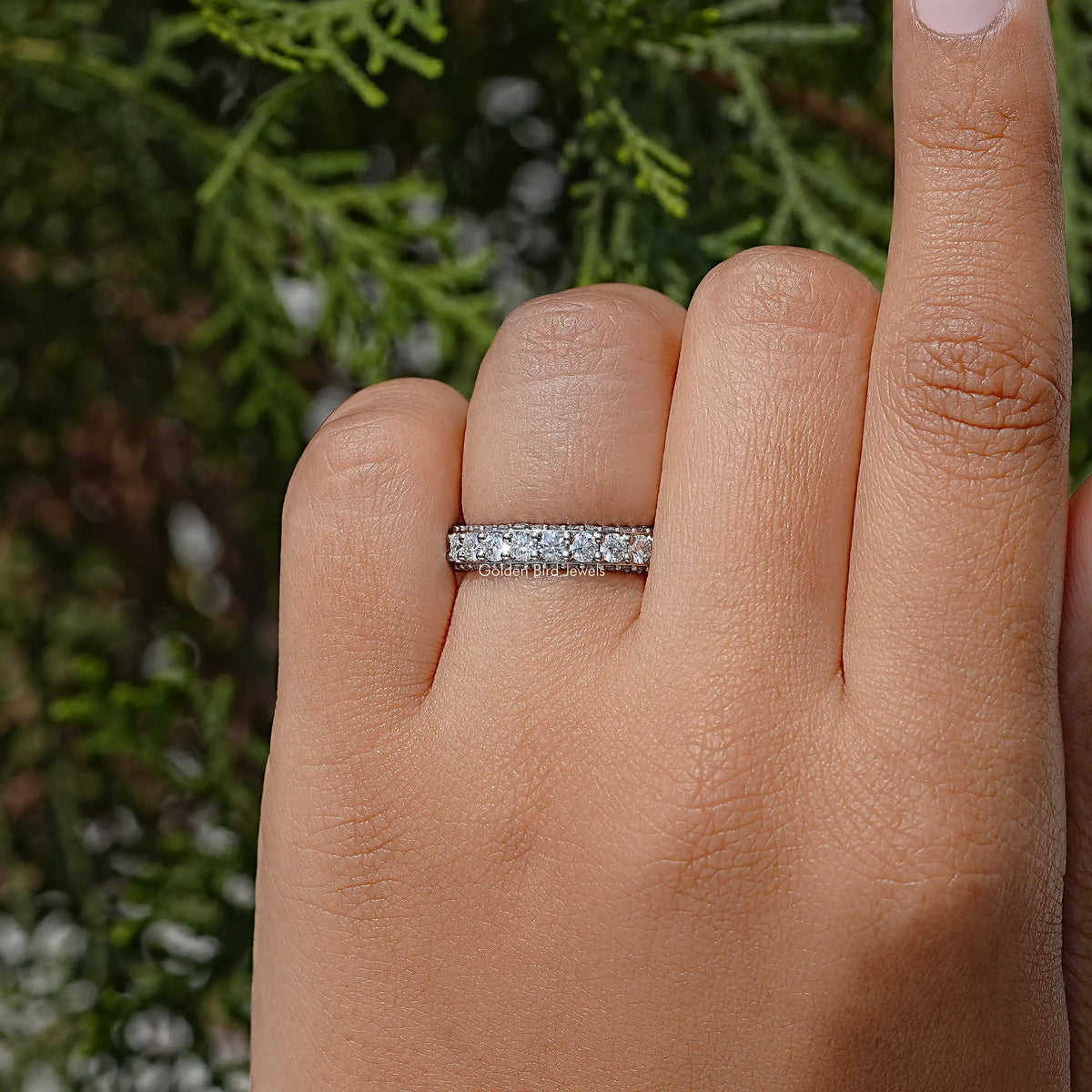 Moissanite eternity band with pave-set round stones on a finger