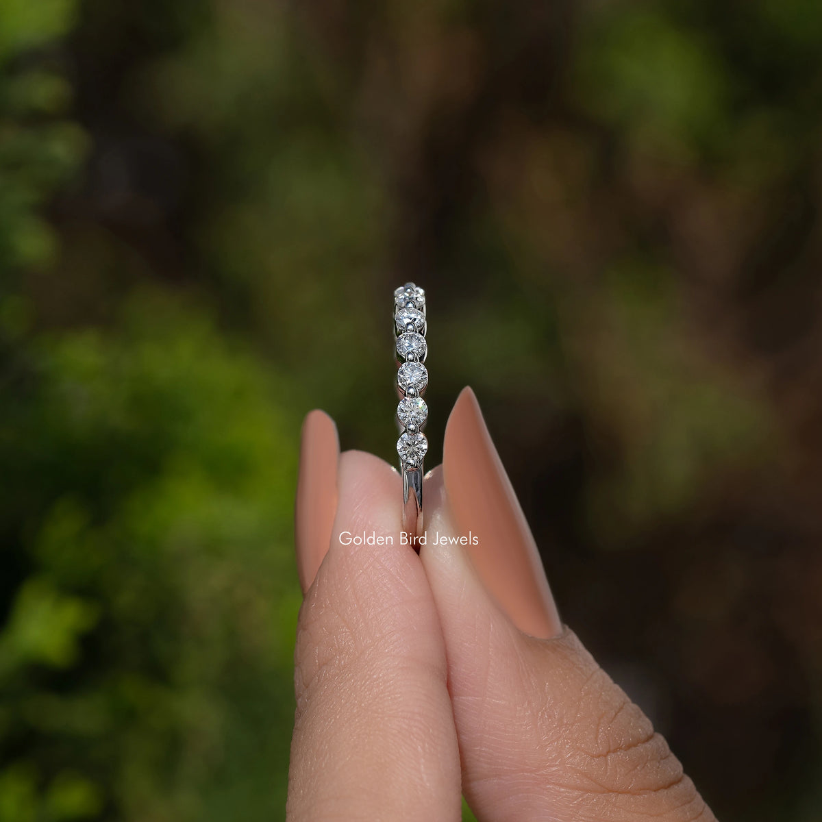 Round moissanite half eternity band with sparkling stones, shown from the side