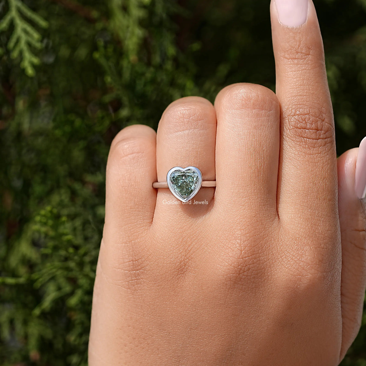 Heart-shaped moissanite bezel ring with slim sterling band on hand, side view