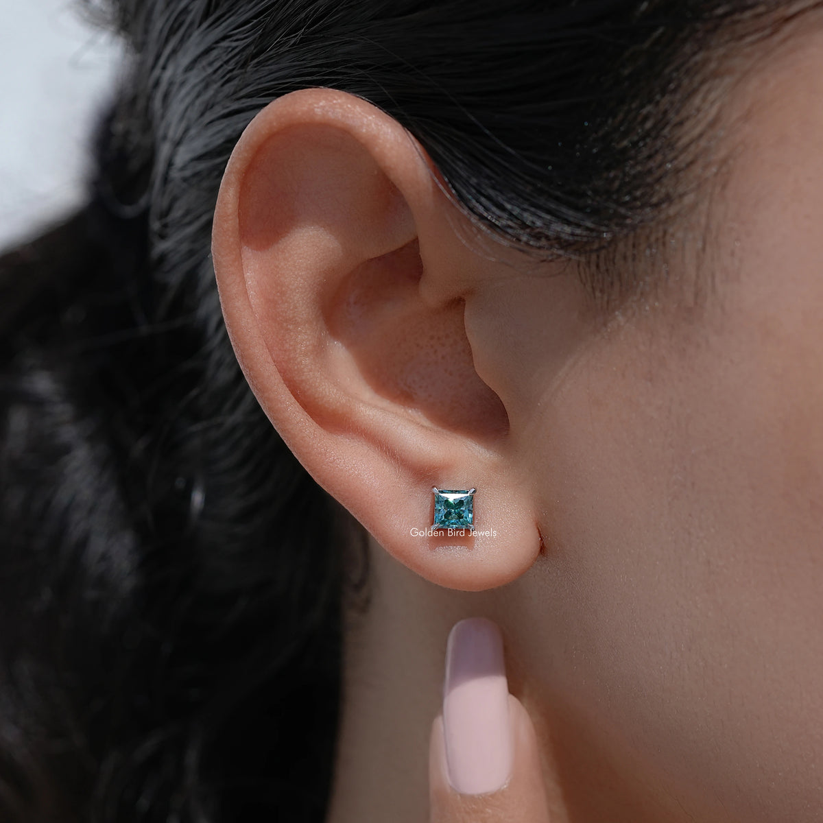 Blue square princess-cut screw-back stud earring detail on ear