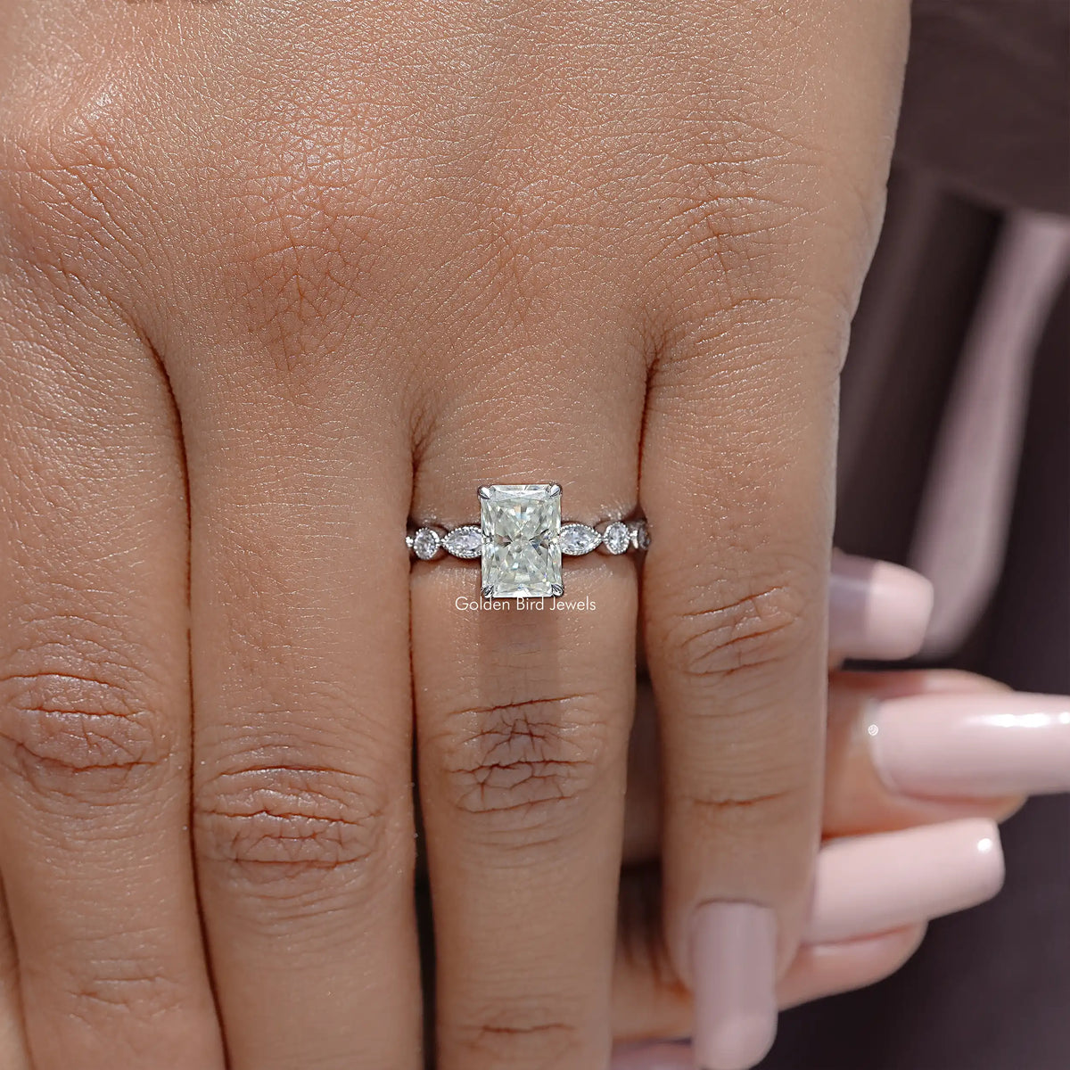Radiant cut moissanite engagement ring, square center with small side accents, on finger