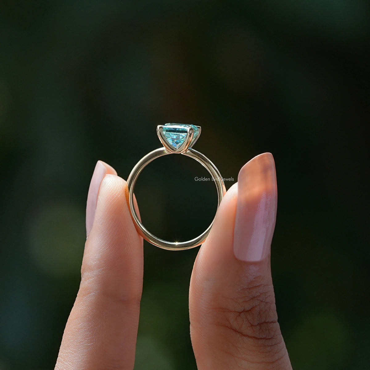 Silver princess-cut solitaire ring with cyan-blue square stone top view, prongs visible