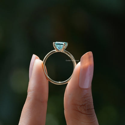 Silver princess-cut solitaire ring with cyan-blue square stone top view, prongs visible