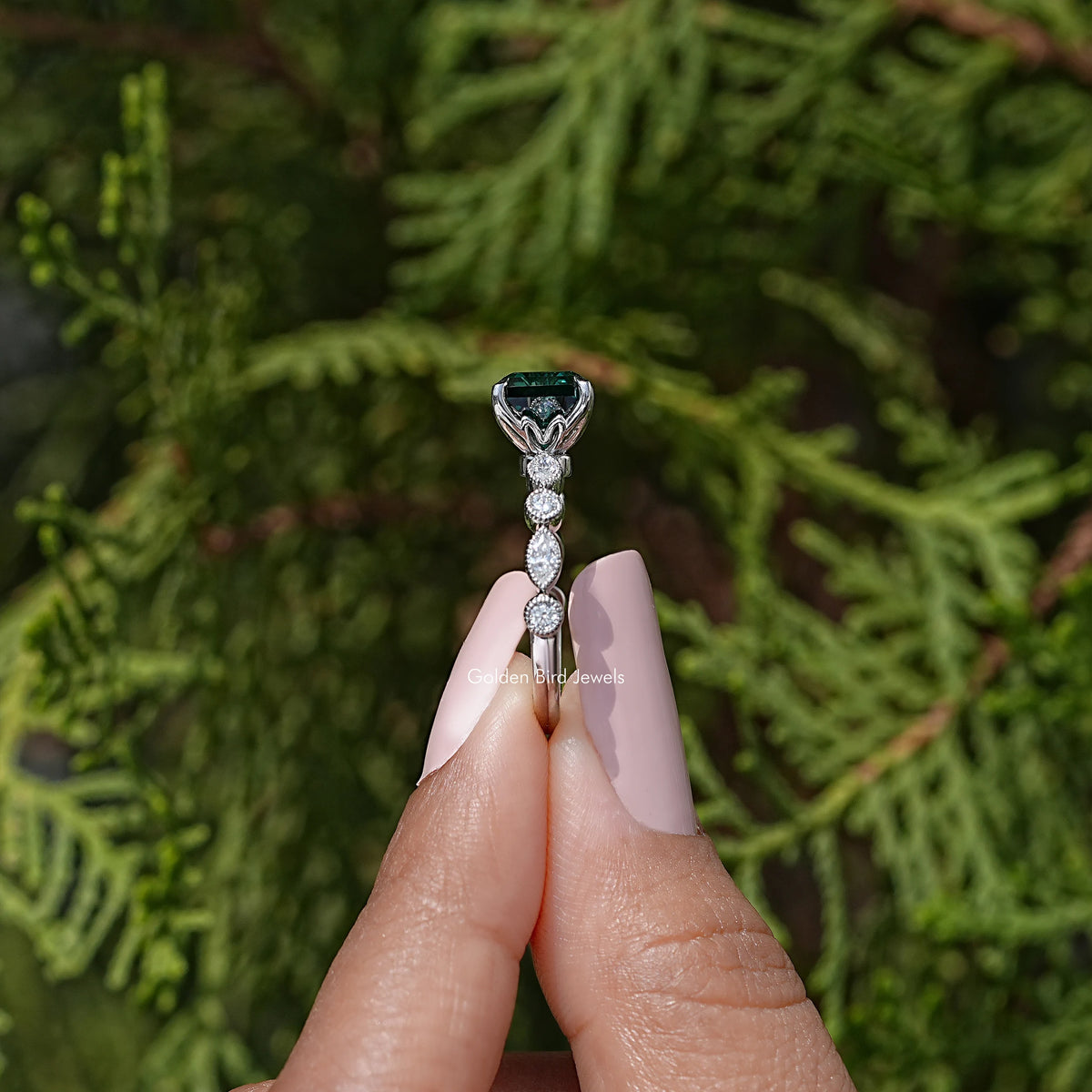 Top view: green Asscher-cut moissanite center stone with prongs and small round details, silver