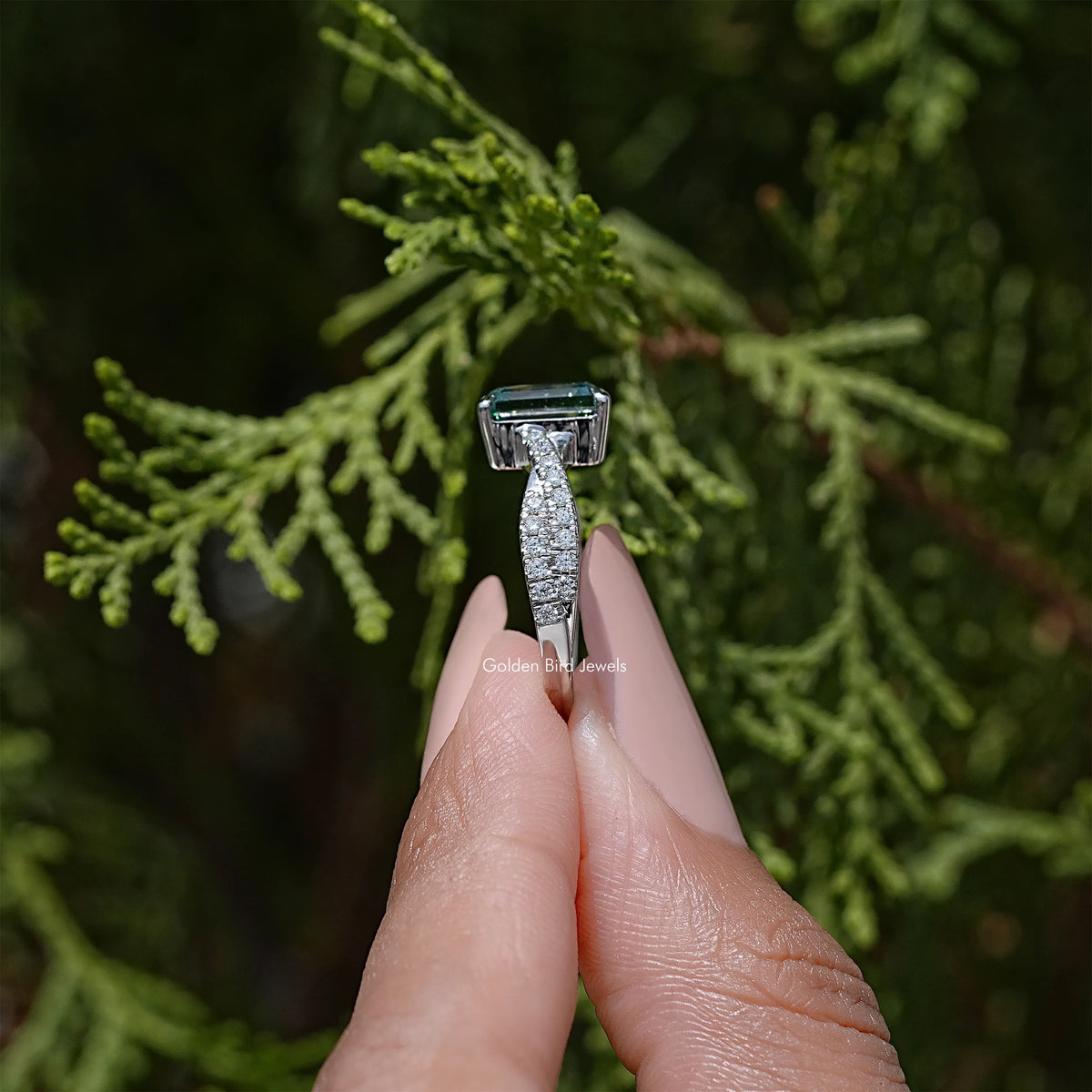 Twisted silver wedding ring holding an emerald-cut teal moissanite center stone