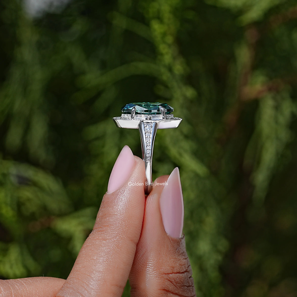 Top view of silver halo ring with dark green oval center gemstone and halo