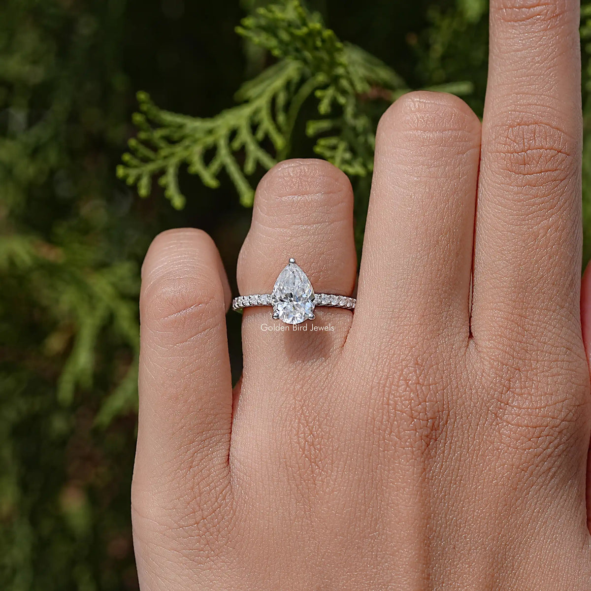 Pear-cut solitaire accent wedding ring on a hand