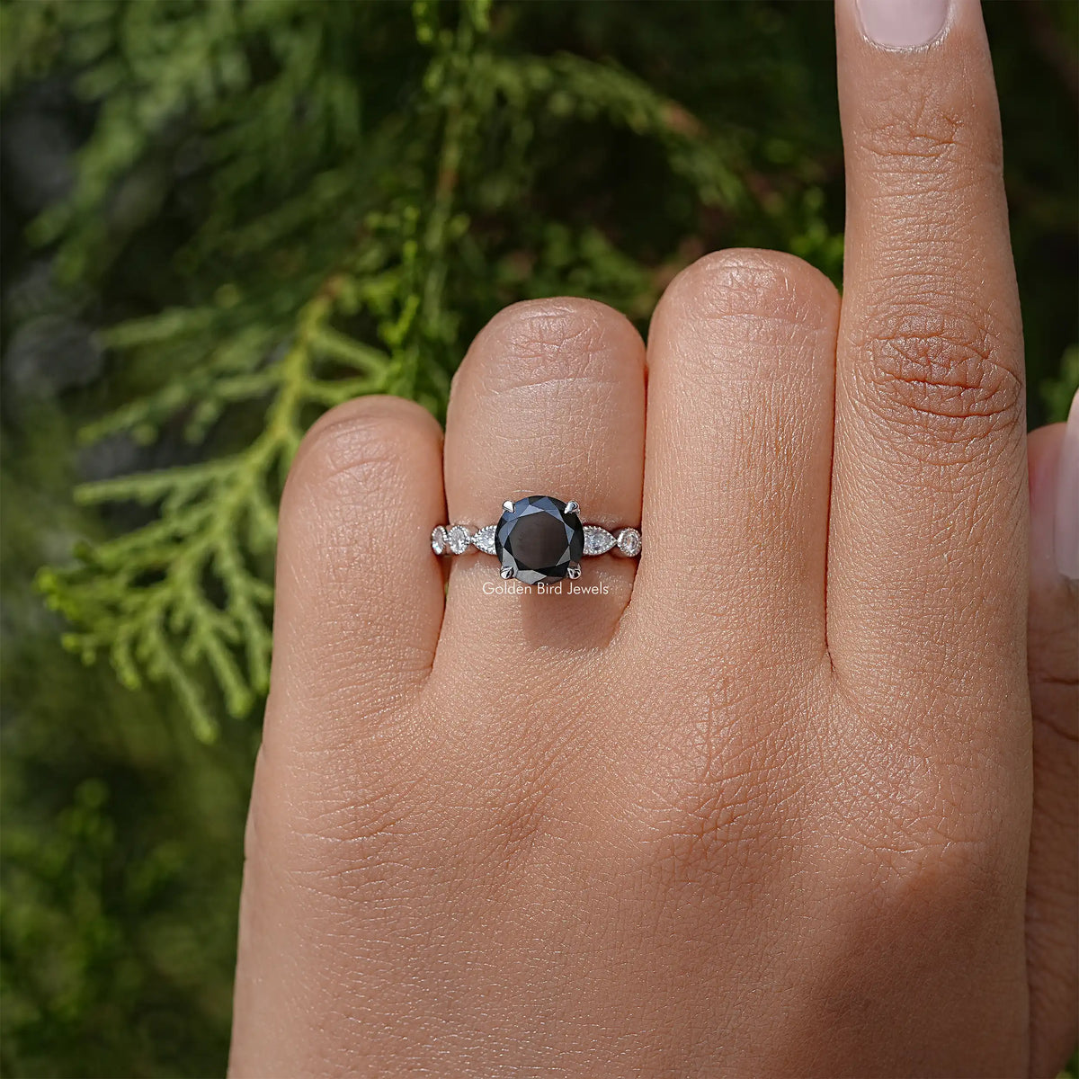 Moissanite engagement ring with dark center stone and side stones on a silver band