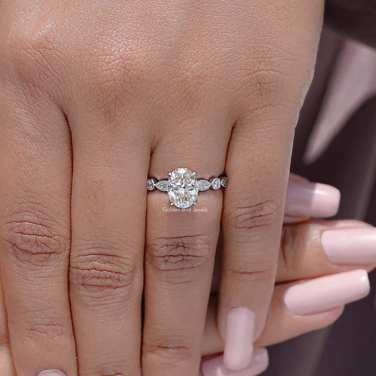 Sterling silver oval moissanite ring with round side stones, centered on finger