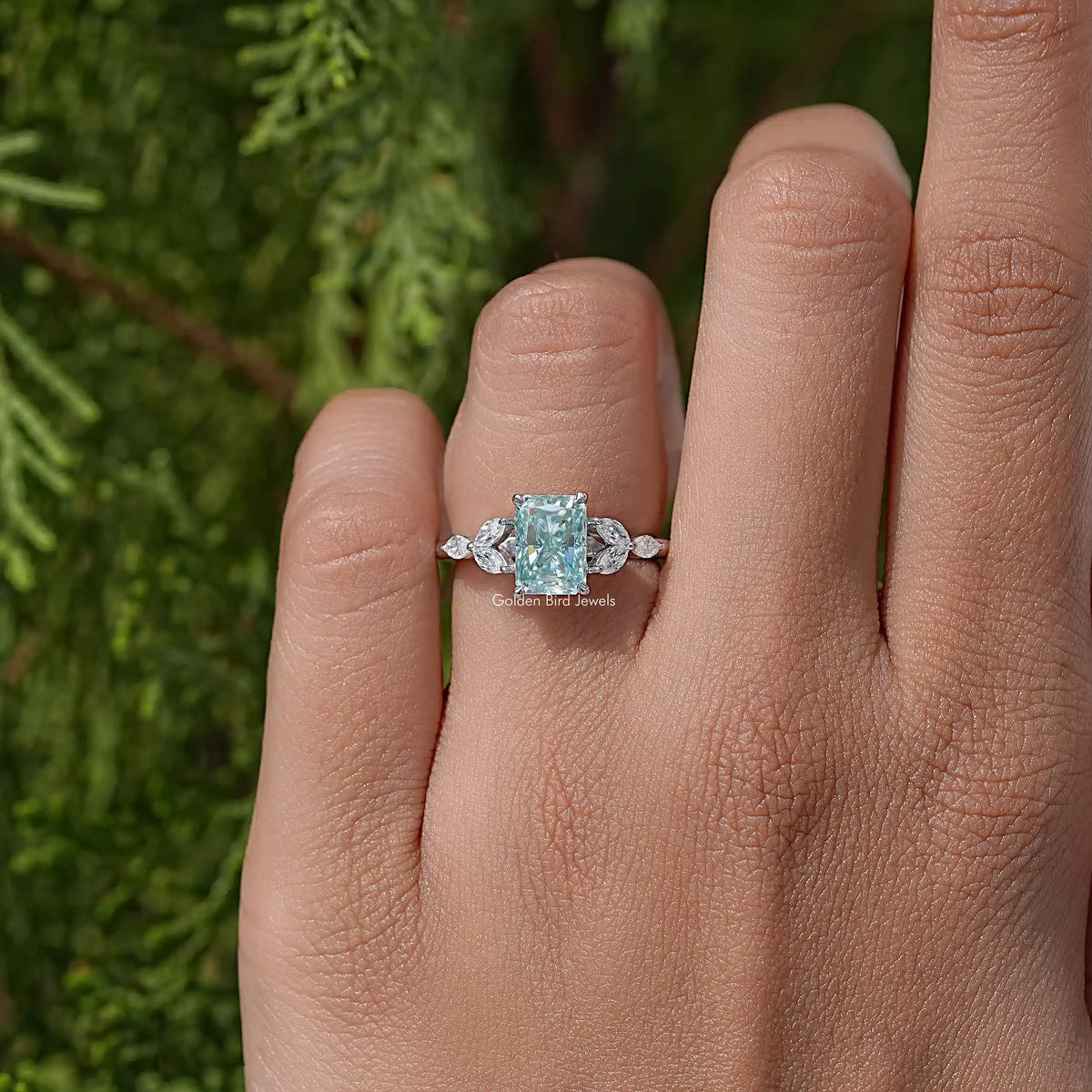 Sterling silver engagement ring with cushion-cut blue-green moissanite center on hand