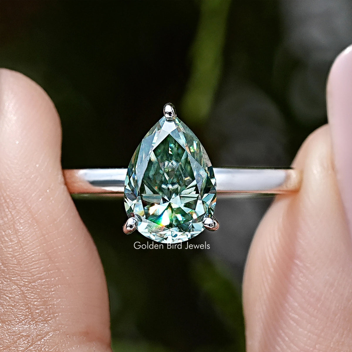 Sterling silver pear-shaped moissanite ring with green stone and side prong view