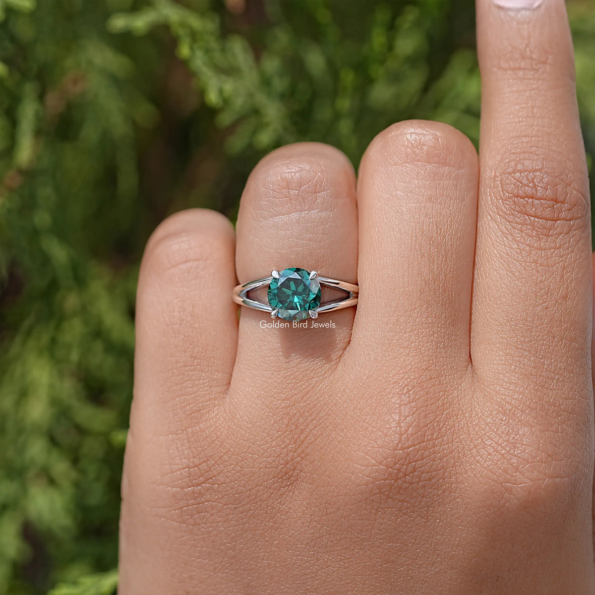 Sterling silver split-shank engagement ring with round teal moissanite center, front view