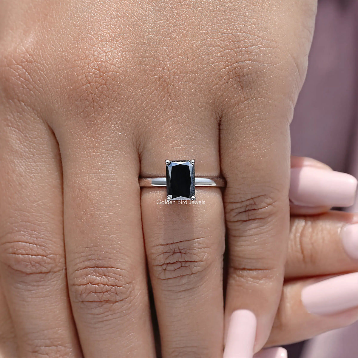 Silver ring close-up on finger, square black radiant-cut stone with halo setting