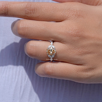 Oval moissanite ring with leaf side stones, center stone tilted in hand close-up
