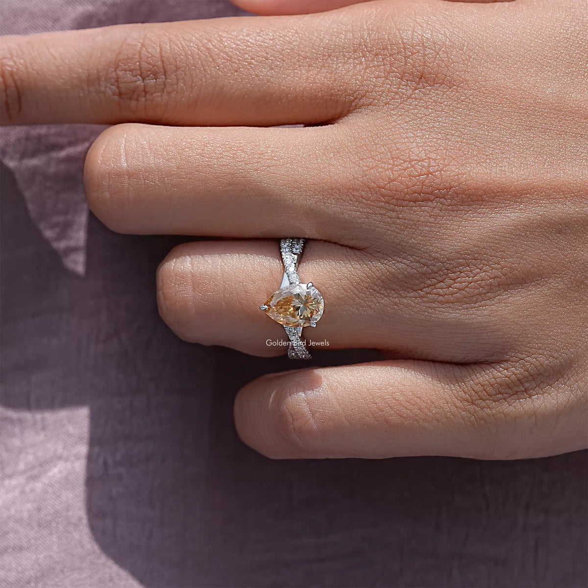 Pear moissanite twisted shank accent ring on a hand