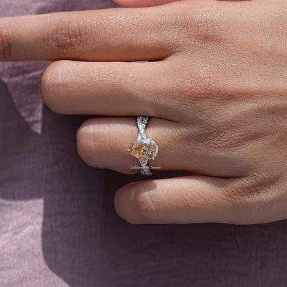Pear moissanite twisted shank accent ring on a hand