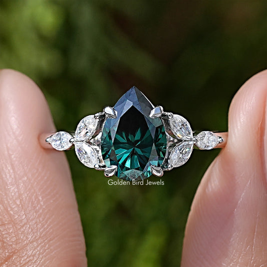 Close-up sterling silver ring with green pear-cut moissanite and round diamond halo