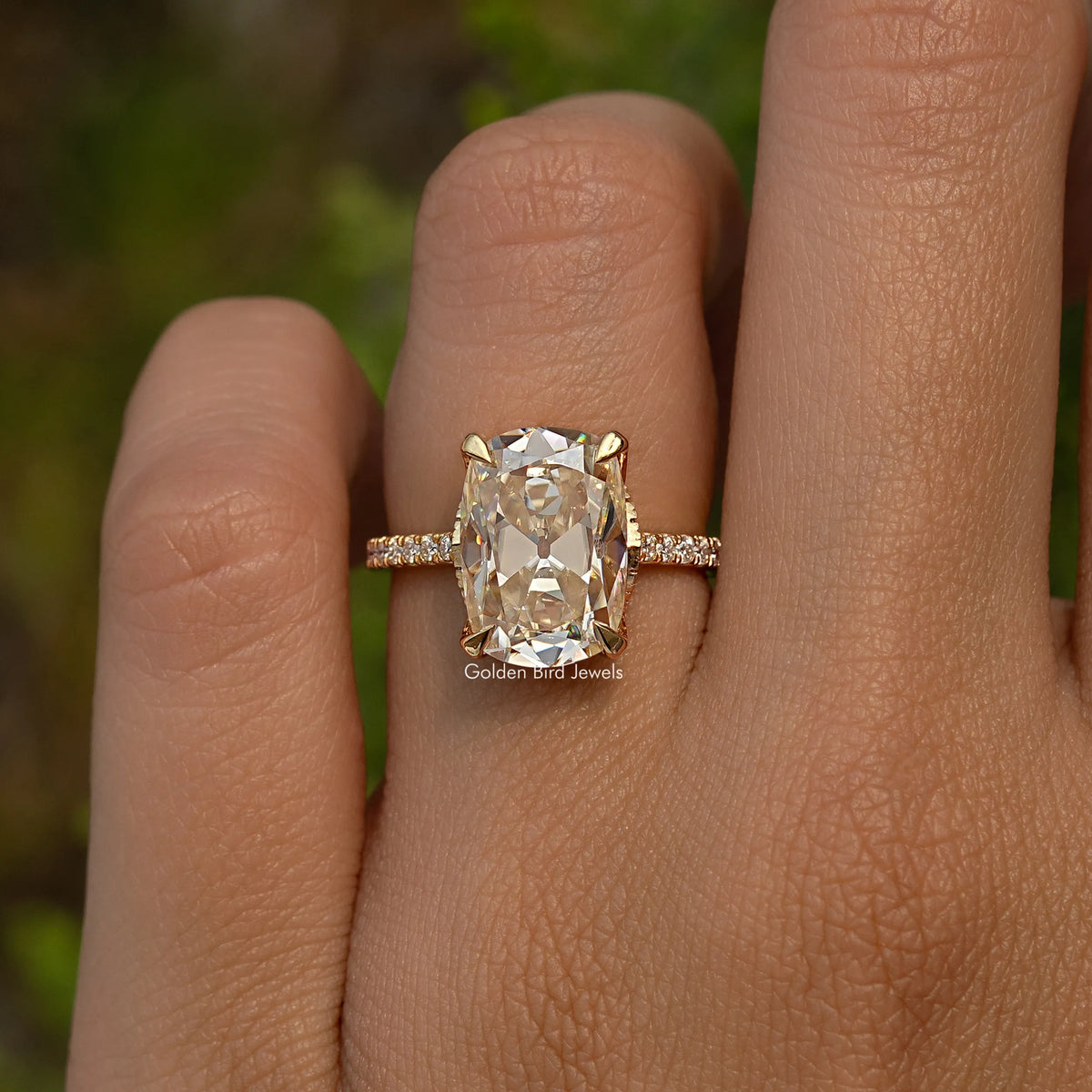 Elongated cushion moissanite engagement ring on hand, hidden halo and side stones