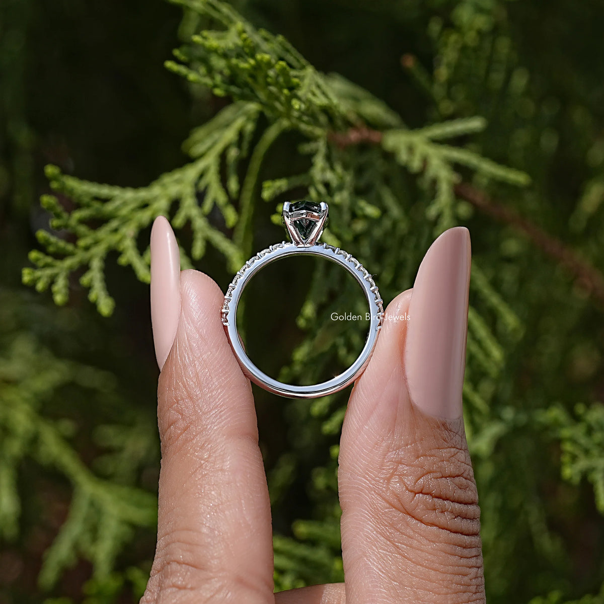 Marquise green moissanite solitaire accent ring with round halo-like frame, on hand.