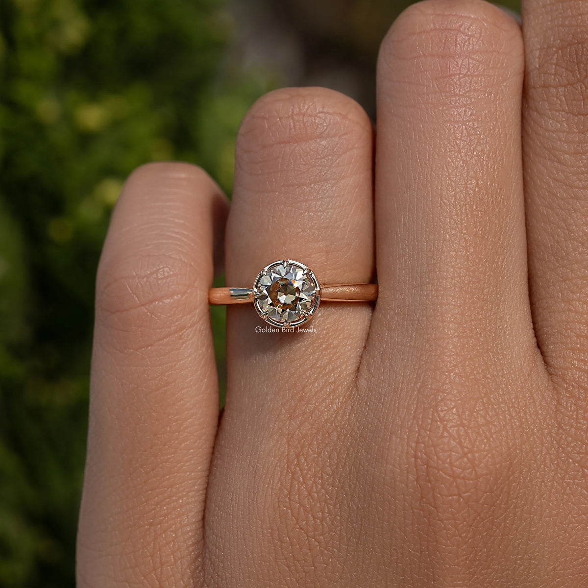 Round moissanite ring with gold-tone band and prong-set round stone on hand