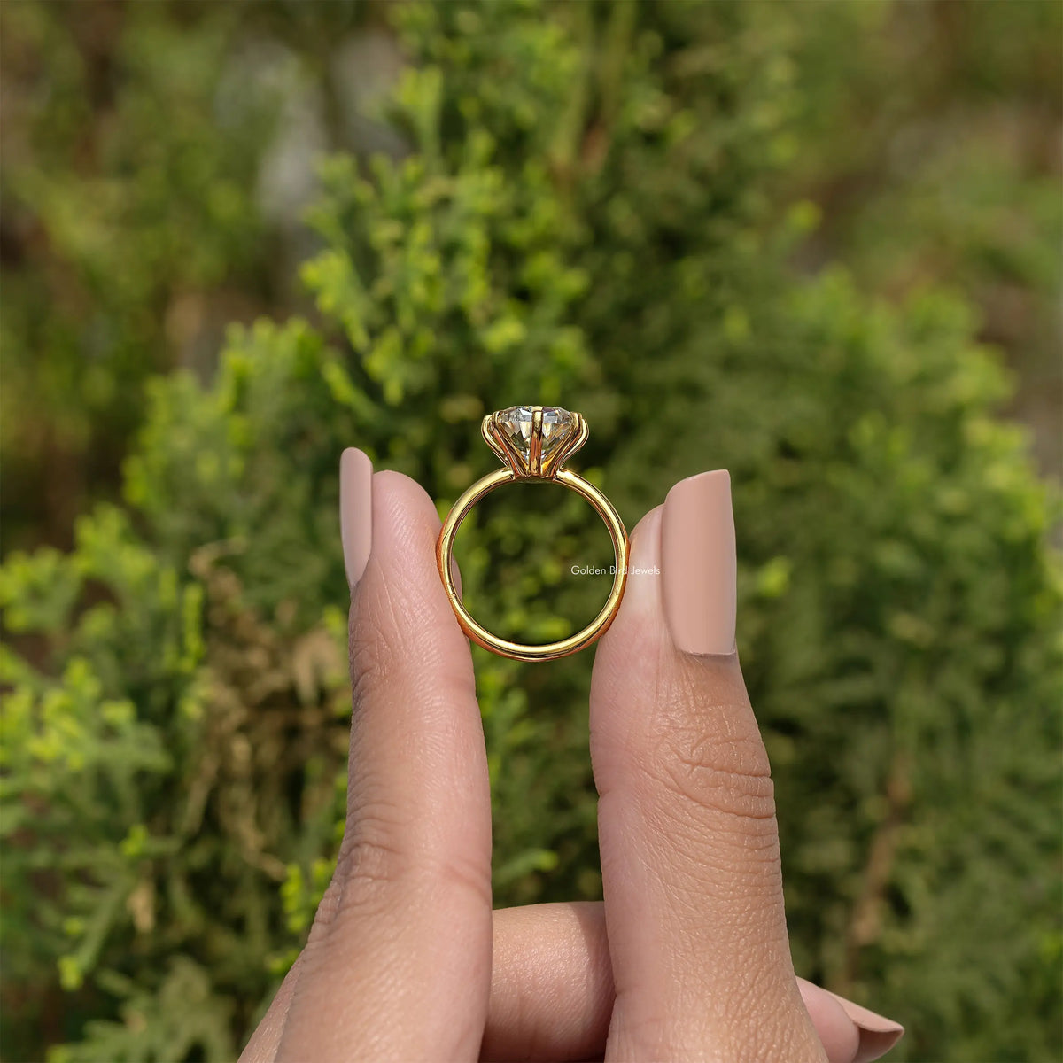 Gold-tone cushion solitaire ring with halo-like prongs, center stone, side view on hand