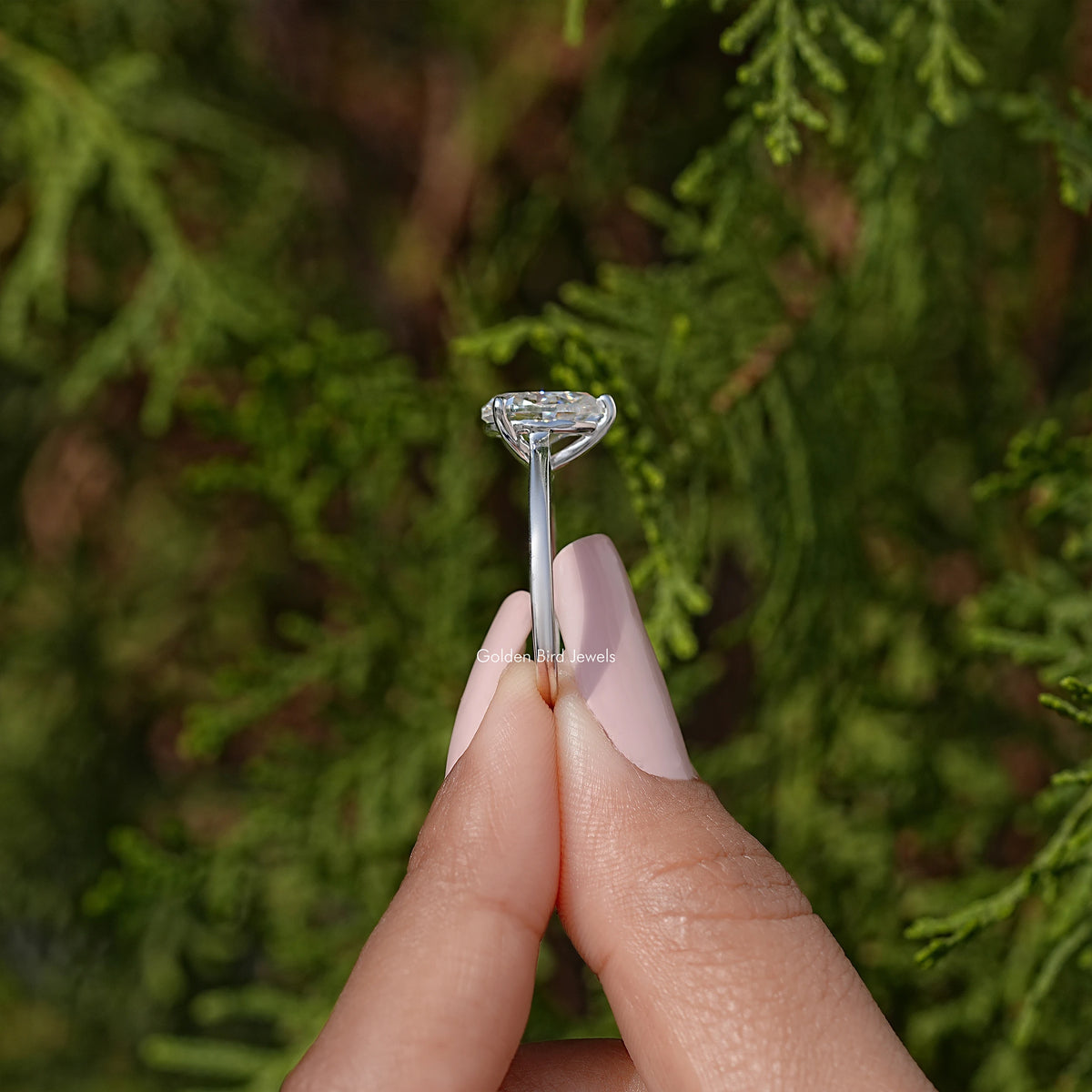 Pear-cut solitaire engagement ring top view, clear stone in prong setting, silver band