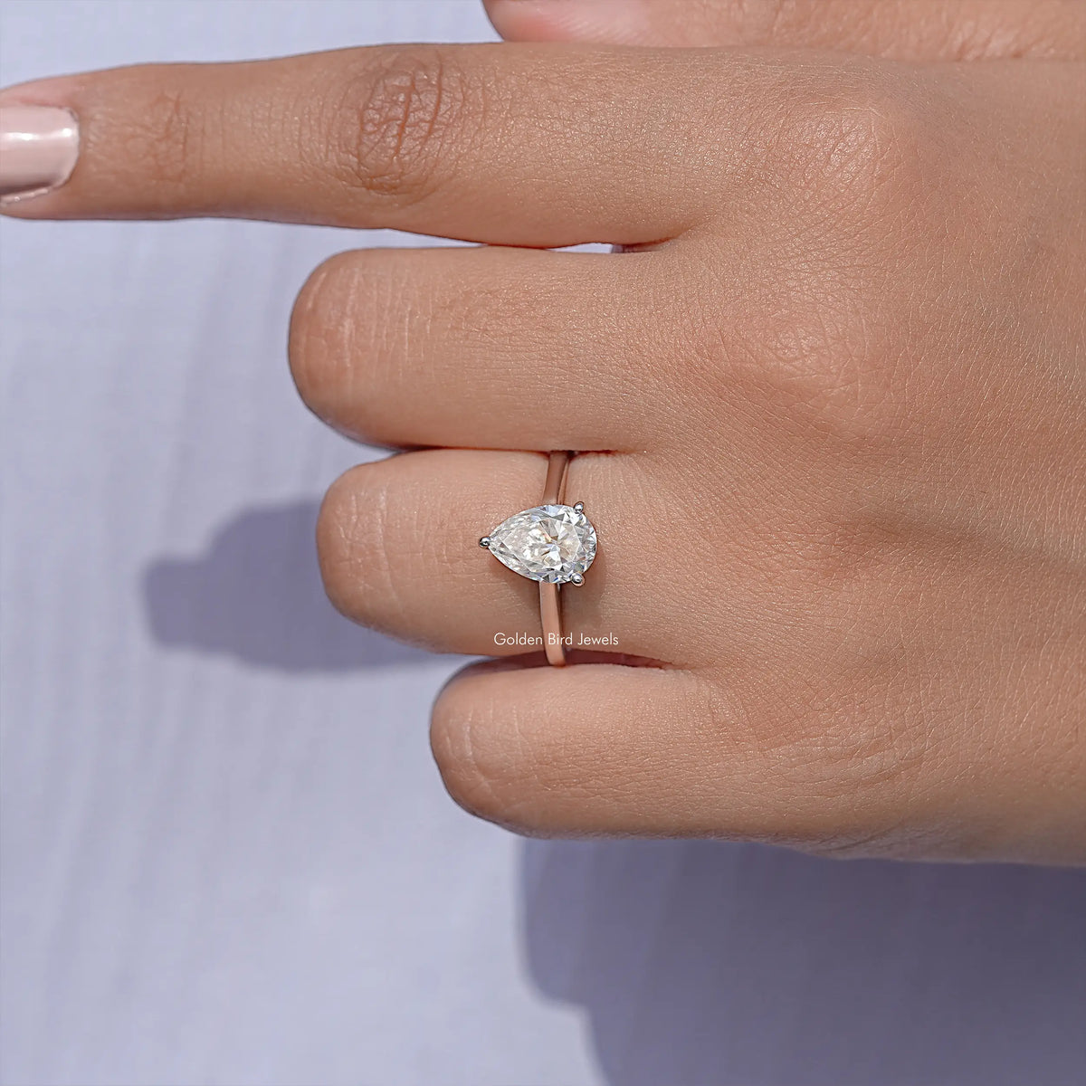 Pear-cut solitaire engagement ring close-up, clear teardrop stone and visible prongs, silver
