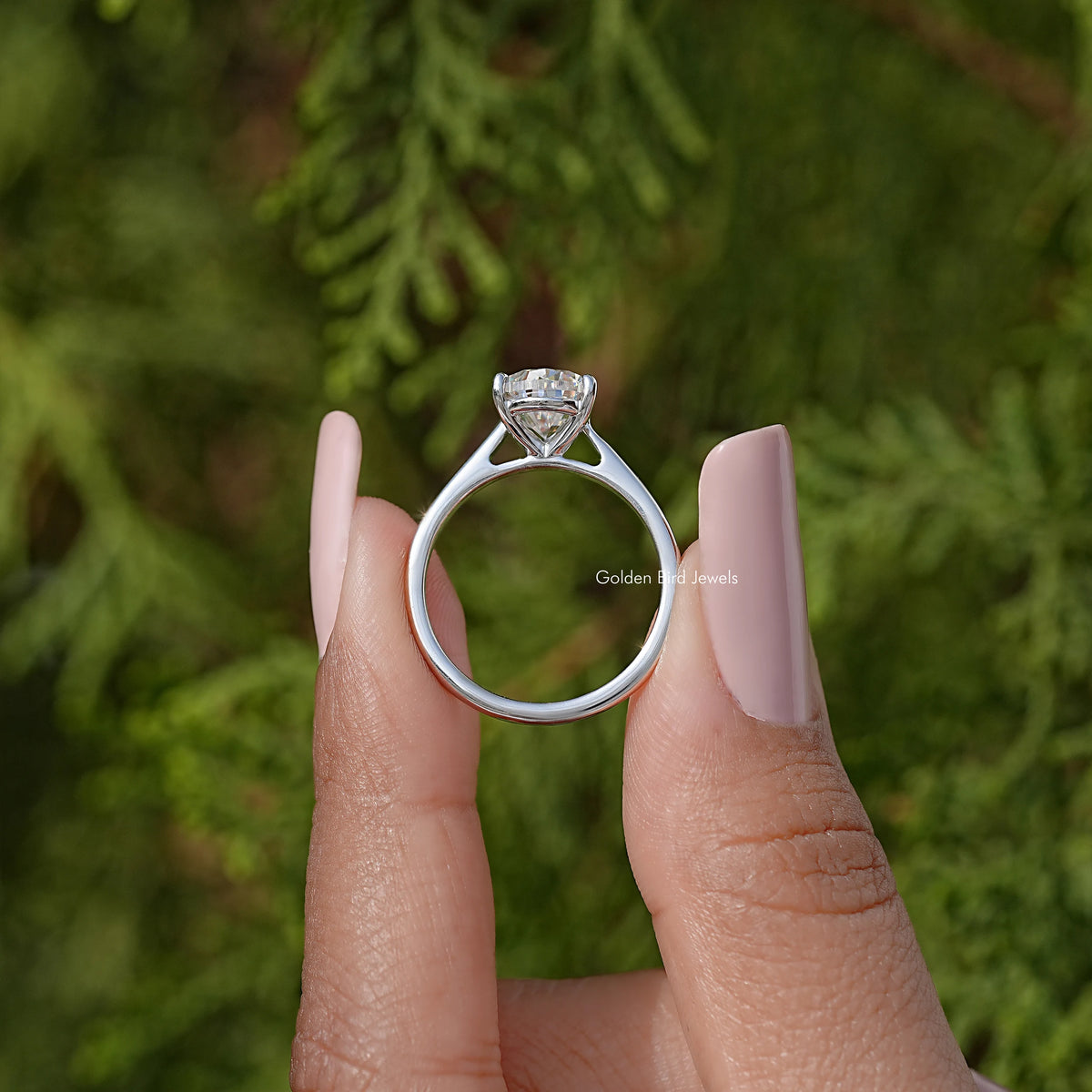 Pear-cut solitaire engagement ring with clear teardrop stone, silver band on finger