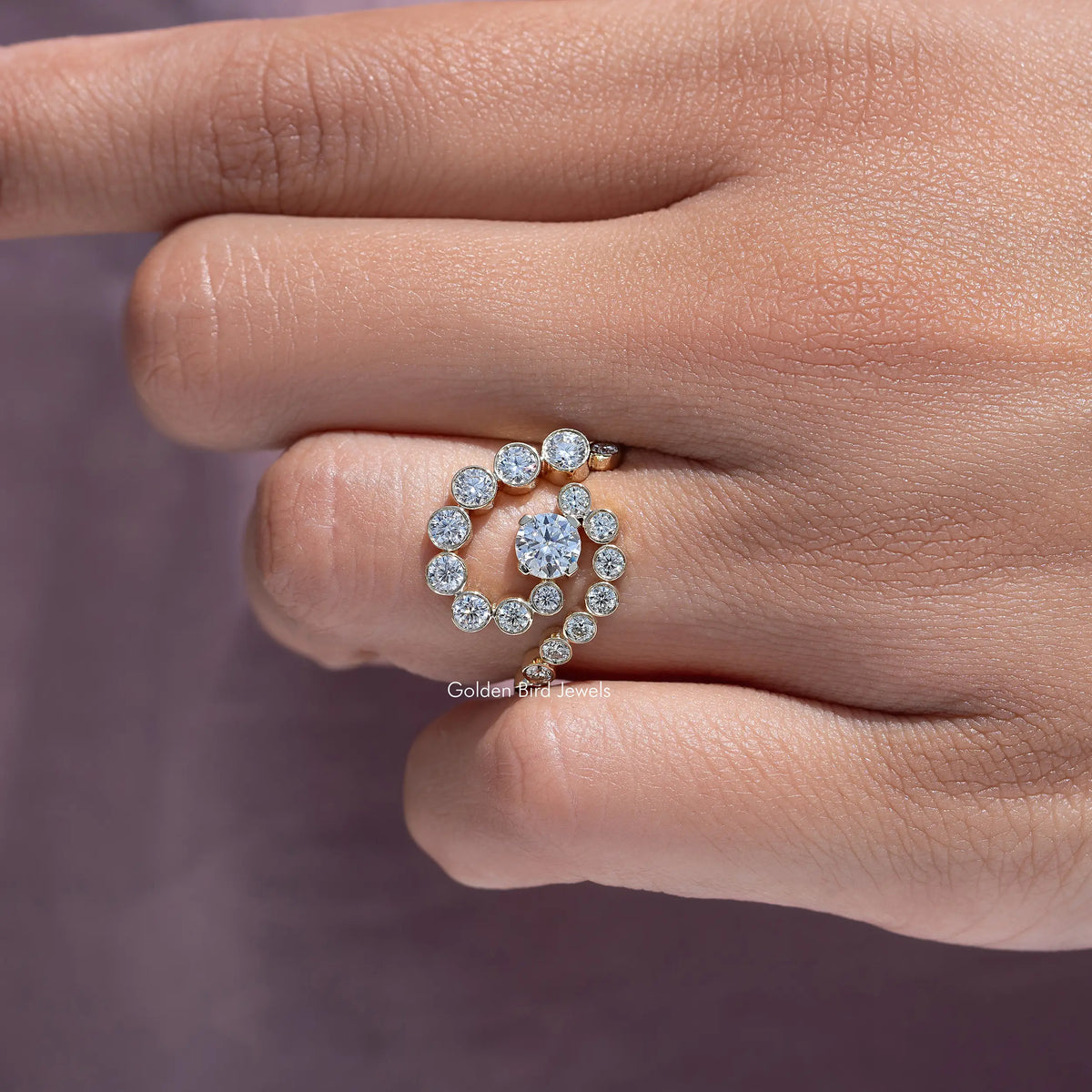 10k yellow gold moissanite ring with round center stone and spiral halo, on finger