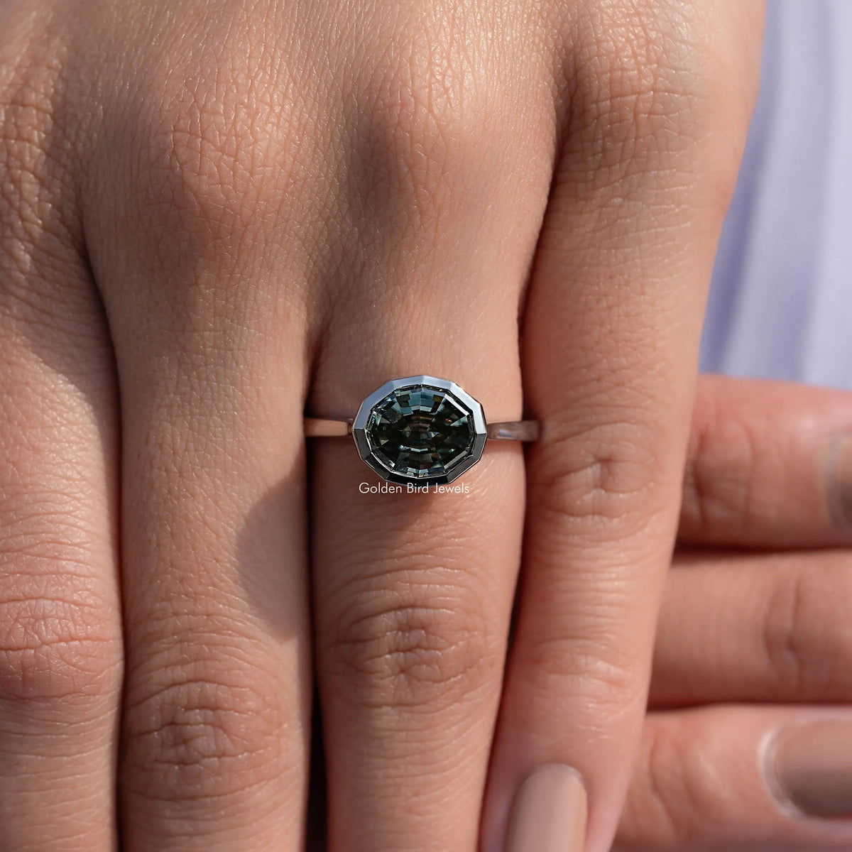 Bezel-set solitaire ring with dark green step-cut gemstone in an octagonal bezel